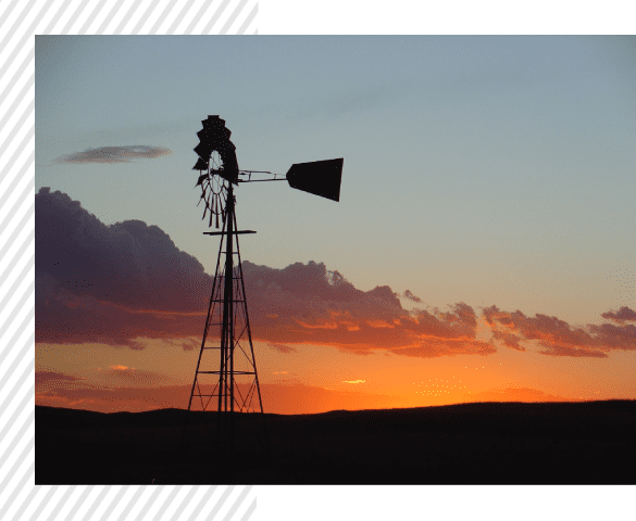 A windmill is in the middle of an open field.